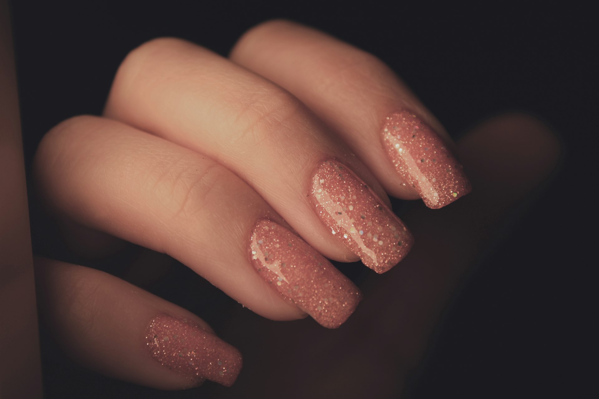 La mano de una mujer con una manicura rosa.